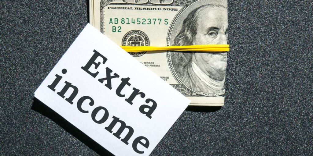 A stack of USD tied with a rubber band with a paper labeled 'Extra Income,' representing if beginners can earn from Forex trading.